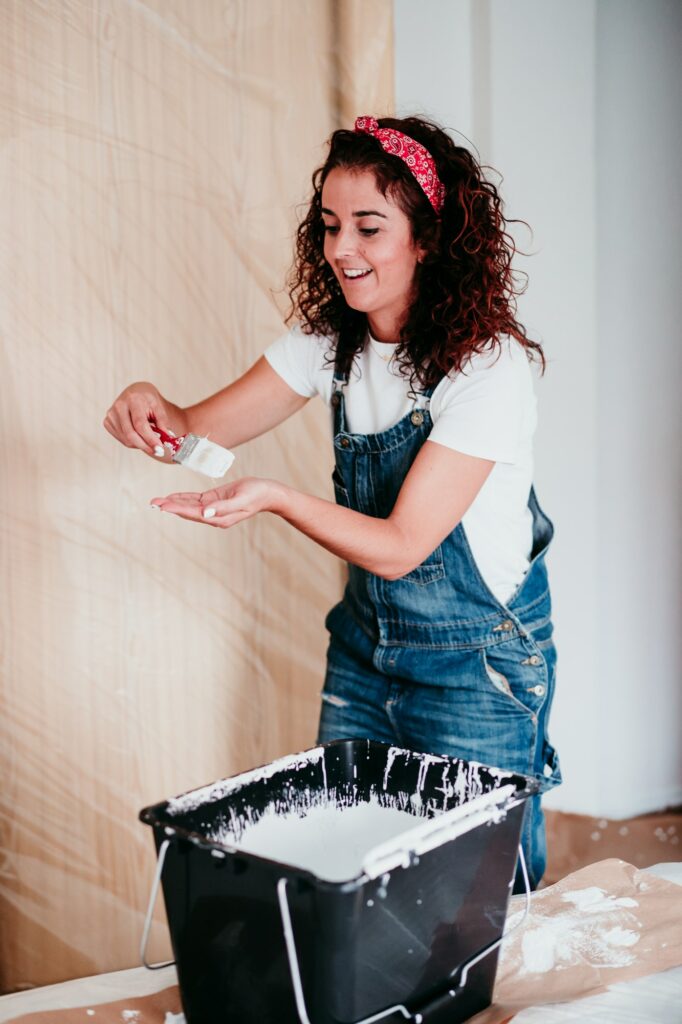 happy caucasian woman painting the room walls with white color. Do it yourself and new home concept